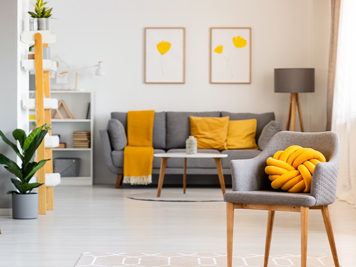 grey living room couch and chair with yellow accent pillows and blanket